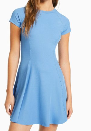 Mujer con un vestido azul claro ajustado de manga corta y acanalado, con falda acampanada, mostrado desde la mitad del muslo hasta los hombros.