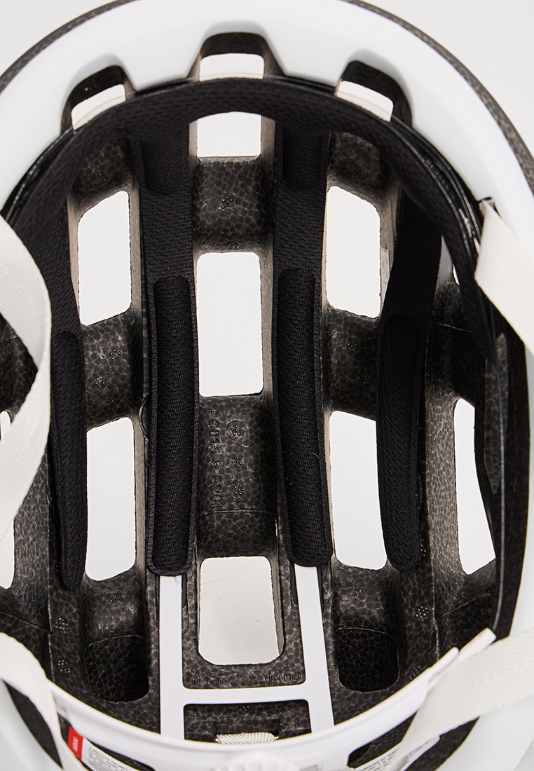 Interno di un casco da bicicletta con un guscio esterno bianco, imbottitura nera e fori di ventilazione. Presenta un materiale nero testurizzato e cinghie bianche.