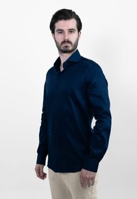 Marineblauw overhemdd met een gladde textuur, lange mouwen en een puntige kraag, aangevuld met een standaard pasvorm en bijpassende knopen.