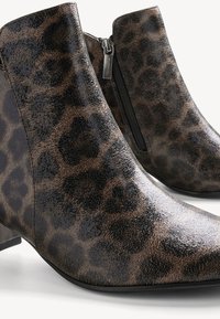 Botine cu imprimeu de leopard și finisaj lucios, dotate cu un fermoar lateral și un toc mic, texturat. Material neted cu modele pronunțate.