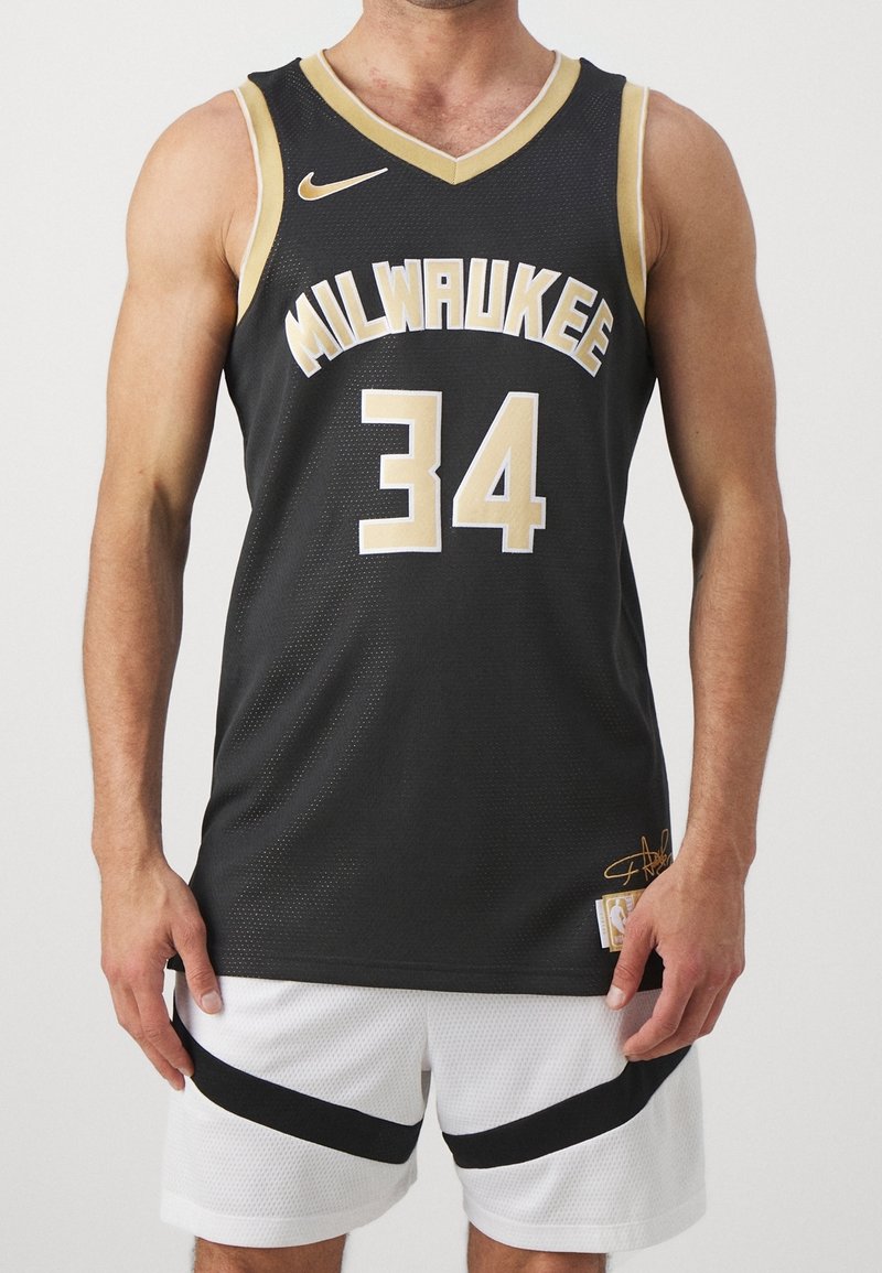 Athlète portant un maillot de basket-ball noir de Milwaukee numéro 34 et un short blanc avec des rayures diagonales noires sur un fond clair.