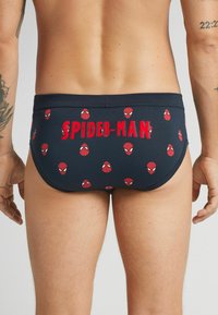 Marinefarbene Schwimmbrieft mit einem sich wiederholenden Muster aus roten Spider-Man-Masken und dem Text "SPIDER-MAN" in roten Buchstaben.