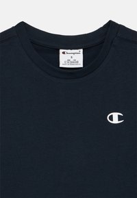 Μπλε βαμβακερό t-shirt σε ναυτικό μπλε χρώμα με στρογγυλή λαιμόκοψη. Φέρει μικρό λευκό λογότυπο Champion στην αριστερή πλευρά. Η ετικέτα υποδεικνύει μέγεθος S.