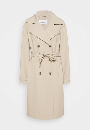 Béžový trench coat vyrobený z hladké látky. Vybavený dvouřadým zapínáním, širokými klopami, pasem na opasek a bočními kapsami.