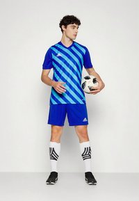 Sinine jalgpallimärk diagonaaltriibulise mustriga, millele sobivad sinised lühikesed püksid, mustad jalgpalliketsid ja valged sokid mustade triipudega.