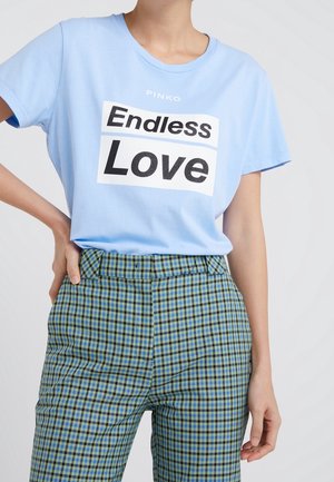 Hellblaues Baumwoll-T-Shirt mit schwarzem und weißem grafischem Schriftzug "Endless Love", kombiniert mit grün-blau karierten, hoch taillierten Hosen.