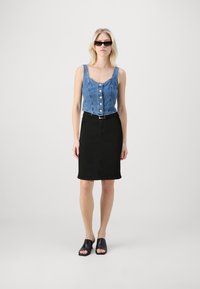 Denim crop top with buttons, black fitted skirt, and open-toe black shoes, featuring a simple and contemporary design.