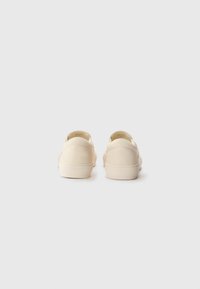 Beige slip-on sko med en glat overflade, rund bag, tykke såler og diskret syning. Minimalistisk design uden synlig branding.