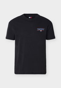 Μαύρο T-shirt με κοντά μανίκια και μικρό λογότυπο "Tommy" σε μπλε και κόκκινο στην αριστερή πλευρά του στήθους, με ένα μικρό έμβλημα σημαίας από κάτω.