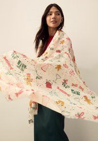 Lightweight, sheer scarf featuring festive patterns in red, green, and gold on a cream background. Edges are frayed for texture.
