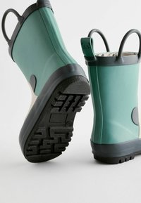 Bottes en caoutchouc vertes avec semelles et contours noirs. Dotées de poignées doubles et d'un motif de panda ludique sur la sangle. Semelle texturée et robuste.