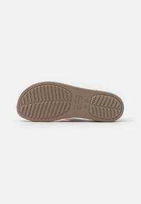 Semelle d'une chaussure Crocs marron clair avec motif de traction texturé et marquages de taille sur fond blanc.