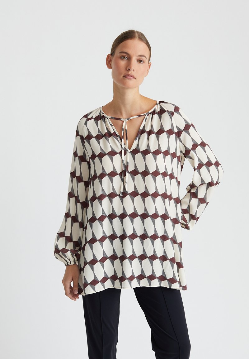 Lange mouwen blouse met een geometrisch patroon in ivoor, bordeauxrood en donkergrijs. Heeft een V-hals met een strikdetail en een losse, vloeiende pasvorm.