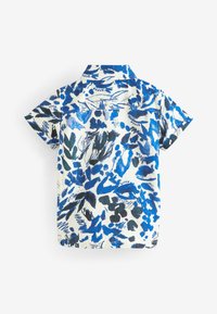 Camisa de manga corta con fondo blanco y patrones florales en azul y negro, fabricada en algodón y con un diseño de cuello clásico.