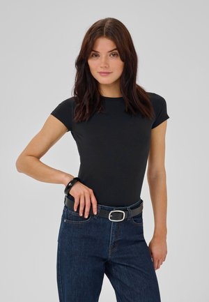 Sort, tætsiddende t-shirt med kortærmer, parret med mørke denimjeans og et sort bælte med en sølvspænde, båret afslappet.