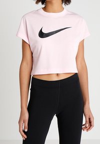 Rosa kortärmad T-shirt med en svart Nike-logotyp på framsidan. Korta ärmar och en standard rundad halsringning. Matchas med svarta leggings.