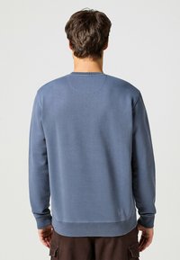 Blå sweatshirt i bomullsblandning, med långa ärmar, rund halslinning och en jämn textur med minimala sömdetaljer.