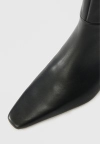 Schwarze Lederknöchelstiefel mit spitzem Zehen und glatter Textur, minimalistischem Design und ohne sichtbare Hardware oder Akzente.