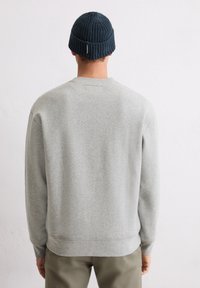 Grijze sweatshirt met geribde manchetten, ronde hals en een reguliere pasvorm. Draagt een donkerblauwe geribde gebreide beanie. Eenvoudig, strak design.