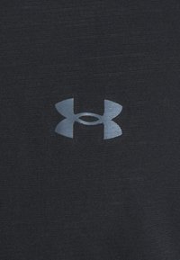 Black fabric with a textured finish featuring a silver Under Armour logo at the center, showcasing a dual oval and triangle design.