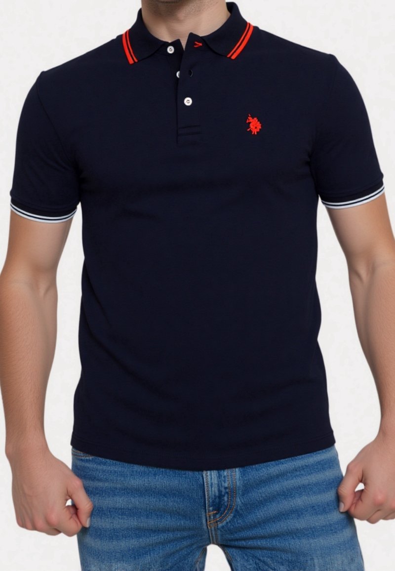 Homme portant un polo bleu marine avec des rayures rouges sur le col, un logo rouge sur la poitrine gauche, une bande blanche sur les bords des manches, assorti à un jean bleu.