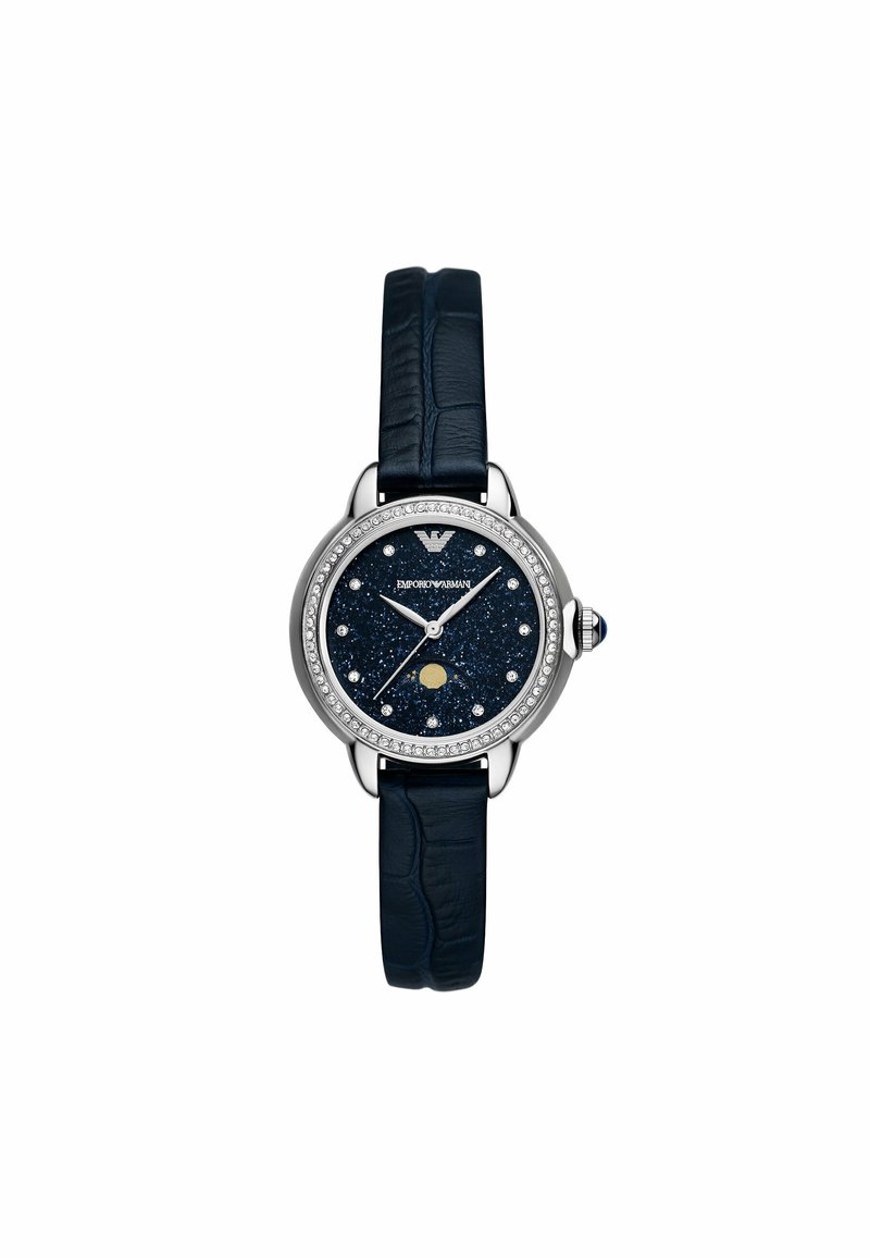 Reloj con correa de cuero azul, caja redonda de acero plateado, esfera con purpurina marina, acentos de cristal y agujas plateadas, que presenta un detalle de fase lunar.