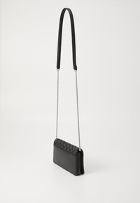 Borsa a tracolla in pelle nera con una texture trapuntata sul davanti, dotata di una tracolla a catena removibile e di una forma rettangolare elegante.
