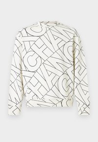 Λευκή μπλούζα με στάμπα από μαύρο γεωμετρικό κείμενο. Έχει στρογγυλή λαιμόκοψη, μακριά μανίκια και ριμπ μανσέτες. Μαλακό υλικό και άνετη γραμμή.