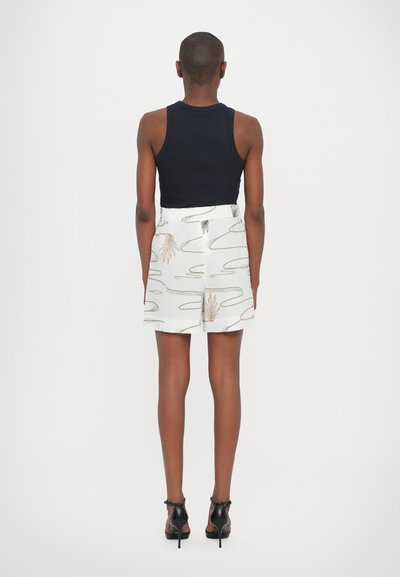 Μαύρο ριγωτό τοπ συνδυασμένο με λευκό σορτσάκι με σχέδια κυματιστών γραμμών και εικονογραφημένες χούφτες, συμπληρωμένο με μαύρες ψηλές γόβες.