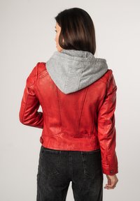 Rode leren jas met een grijze hoodie-voering, slim fit ontwerp en zichtbare stiksels. Gestructureerde afwerking met knoopaccenten. Zwarte jeans.