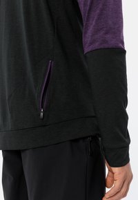 Maglione nero e viola con maniche lunghe, presenta una tasca laterale con zip viola, realizzato in un materiale leggero e testurizzato.