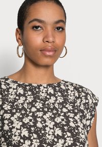 Blusa com estampado floral, apresentando um fundo escuro com flores brancas, mangas curtas, decote redondo e um tecido suave e texturizado.