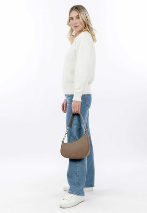 Borsa a tracolla in pelle marrone con un design curvato e dettagli in oro, abbinata a un maglione bianco e jeans blu. Aspetto semplice e moderno.