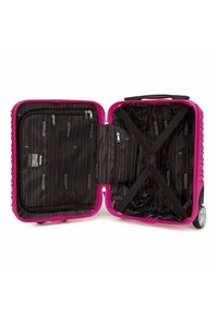 Valigia rigida rosa con apertura a zip, interno organizzato con tasche, rivestimento nero con righe bianche e cinghie incrociate.