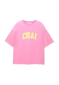 Roze katoenen T-shirt met korte mouwen en een brede halslijn. Bevat gele letters die "CHAI" in een gebogen ontwerp spellen.