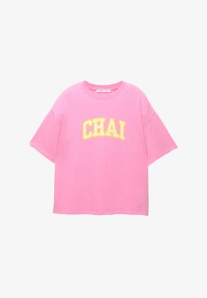 Roze katoenen T-shirt met korte mouwen en een brede halslijn. Bevat gele letters die "CHAI" in een gebogen ontwerp spellen.