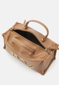 Brązowa skórzana torebka z złotymi elementami, podwójnymi uchwytami i zamkiem błyskawicznym. Posiada zewnętrzną kieszeń na zamek oraz tłoczone logo na przodzie.