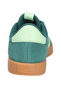 Zapatillas Adidas con una parte superior de ante verde, acentos de cuero menta y una suela exterior de goma. Lengüeta trasera para una fácil puesta.