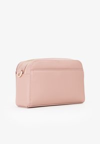 Różowa syntetyczna torba zapinana na zamek z płaskim dnem, gładką teksturą, zaokrąglonymi krawędziami i detalami z hardware w złotym kolorze. Dwie komory na zamek.