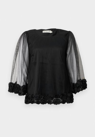 Black blouse with a solid fabric body, tulle puff sleeves, and a floral lace trim at the hem. Features a round neckline and relaxed fit.