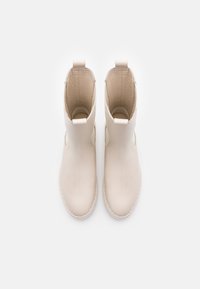 White ankle boots made of smooth leather, featuring a rounded toe, minimalistic design, and small pull tabs at the back for easy wear.