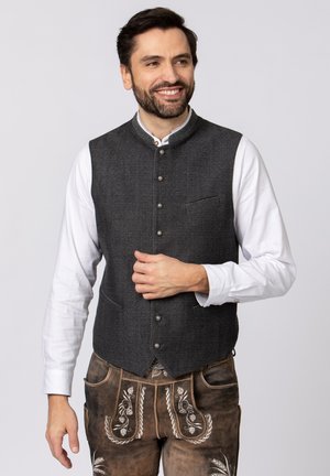 Grau gemusterte Weste mit hohem Kragen, Frontknöpfen und einer Brusttasche, getragen über einem weißen Langarmshirt.