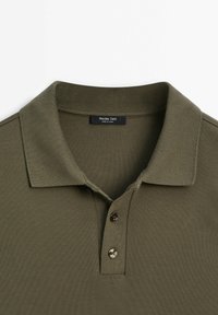 Polo vert olive avec col côtelé, deux boutons sur la patte de boutonnage, et étiquette noire indiquant "Massimo Dutti Made in China".