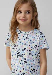 Kurzärmliges T-Shirt aus leichtem Baumwollstoff mit einem mehrfarbigen Blumenmuster auf einem pastellfarbenen Hintergrund und rundem Halsausschnitt.