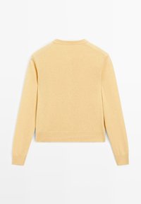 Ljust gult stickat tröja med långa ärmar, rund halsringning och ribbad nederkant. Tyget verkar mjukt och jämnt med minimala designelement.