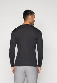 Langermet svart skjorte laget av et glatt stoff, med rund hals og tettsittende design. Bakken viser en strømlinjeformet silhuett og minimale sømmer.
