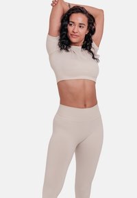 Beige ribbed crop top and high-waisted leggings, made of smooth fabric. The top features short sleeves and a fitted design.