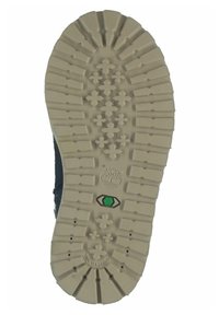 Suela de una bota que presenta un material de goma beige con surcos profundos, una superficie texturizada, acentos verdes y un logotipo en el centro.