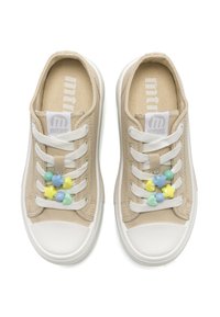 Scarpe da ginnastica in tela beige con suole in gomma bianche, caratterizzate da accentuazioni floreali pastello sui lacci e una toppa con logo sulla linguetta.