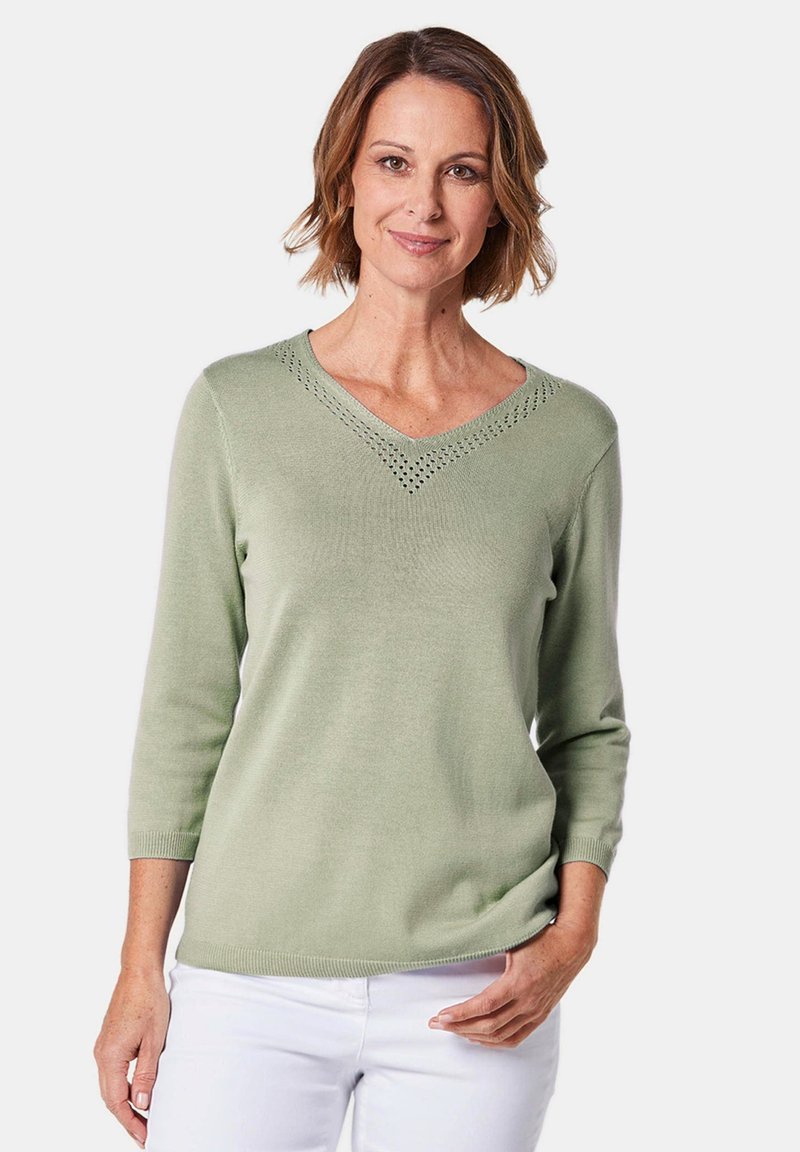 Hellgrüner Pullover mit langen Ärmeln, V-Ausschnitt und Spitzenverzierungen am Hals; weiche Textur und taillierte Form.